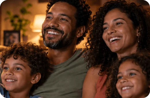 Família sorrindo assistindo filmes juntos em casa